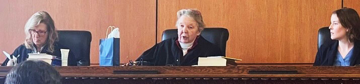 Three women judges sitting on bench for mock trial competition.