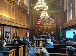 courtroom of people with American flags above judges chambers