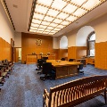 View from southwest corner of remodeled Courtroom 3 featuring gallery bench seating, attorney table with conferencing equipment and tabletop outlets, and additional moveable seating for adaptable uses.